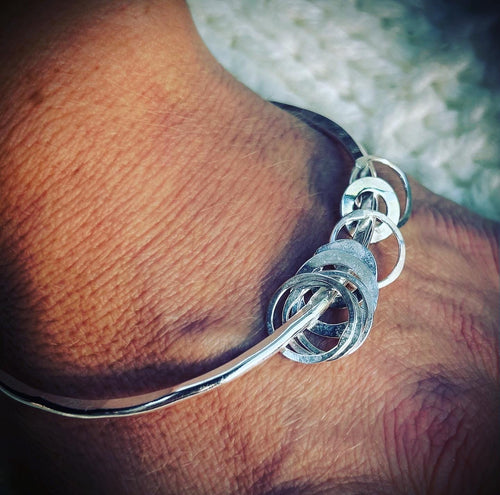 Hammered bangle with multiple silver hoop charms